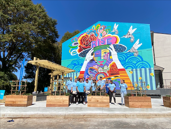 volunteers pose in front of building mural