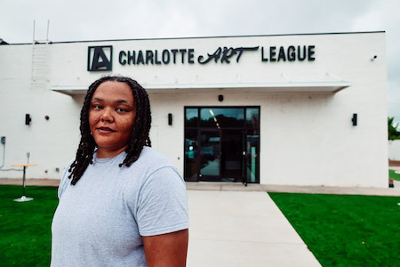 artist poses in front of charlotte art league building