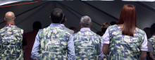 Lowe's workers in camo vests stand in line facing away from camera